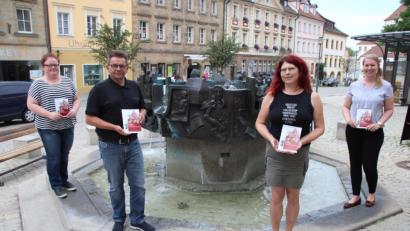 Bild: cog
Am Geschichtsbrunnen auf dem Luitpoldplatz startet die Themenstadtführung „Auf den Spuren der Wittelsbacher“. In der neuen Broschüre „Sulzbach-Rosenberg kennenlernen“, die (von links) Kerstin König (Touristeninformation), Fred Tischler (Kulturwerkstatt), Patrizia Zimmermann (Stadtführerin) und Nina Mutzbauer (Stadtmarketing) hier präsentieren.