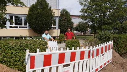 Bild: bkr
Bürgermeister Thomas Kaufmann (links) und Polier Martin Lindner (rechts) freuen sich über den schnellen Baufortschritt. Das Glasfaserkabel für das Leerrohr in der Johann-Baptist-Blas-Straße halten sie an der Baugrube auf dem Schulgelände in der Hand.