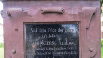 Bild: dob
Das im Jahre 1895 eingeweihte Kriegerdenkmal auf der Mitte des Marktplatzes in Vohenstrauß nennt zwei „tapfere Krieger, die auf dem Felde der Ehre“ verblieben. Auf der schwarzen Glasplatte ist eingraviert: „August Würschinger Soldat d. kgl. 8. Jäger- Bataillons gefallen in der Schlacht b. Sedan a. 1. Sept. 1870.“ Wie die Verlustliste aussagt, verstarb der 25 Jahre alte Krieger nach der Schlacht bei Sedan im Feldlazarett Bazeilles am 6. September 1870 an „durchdringender Brustschusswunde.“ Und das Denkmal erinnert an das zweite Vohenstraußer Opfer: „Jungkunst Andreas „Soldat b. kgl. 9. Jäger Bataillons vermisst in der Schlacht bei Orleans am 8.11.1870.“