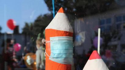 Bild: sfo
Beim Schulstart in Neustadt/WN. Ein Stift, der im Schulhaus ausgestellt ist, trägt einen Mundschutz. Vor der Schule lassen Erstklässler mit ihren Eltern Luftballons steigen. Sie spiegeln sich in der Fensterscheibe.