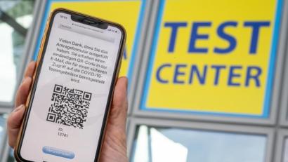 Bild: Peter Kneffel/dpa
Eine Frau hat sich mit ihrem Smartphone für einen Coronatest am Flughafen in München angemeldet.