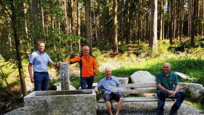 Bild: Forstbetrieb Fichtelberg/exb
Der Namenspatron und die Organisatoren: Bartholomäus Huber (Mitte – mit Schild) hatte die Idee zum Namen „Sehnsuchtsbrunnen“ für den neuen Brunnen am Walderlebnispfad Bischofsgrün. Mit ihm freuen sich Bürgermeister Michael Schreier, Martin Hertel stellvertretender Leiter des Forstbetriebs Fichtelberg und Werner Schmidt, Förster in Bischofsgrün.