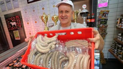 Bild: Karl-Josef Hildenbrand
Matthias Freund hält im Verkaufsraum seiner Metzgerei eine Auswahl seiner verschiedenen Bratwürste.
