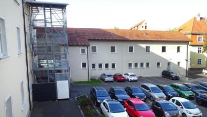 Bild: Houschka
Das ehemalige Werkstattgebäude (im Hintergrund) an der Westseite des Amtsgerichts soll abgerissen und durch einen neuen Trakt ersetzt werden. Mit der Verwirklichung dieser Baumaßahme verschwindet dann das Gerüst mit einer Notfalltreppe (links), das seit einigen Jahren am Hauptgebäude steht.