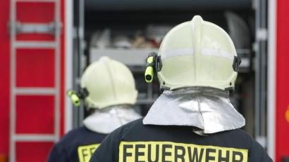 Bild: Stefan Sauer/dpa
Einsatzkräfte der Feuerwehr stehen vor einem Feuerwehrauto.