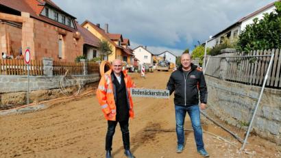 Bild: wpt
Eine Bahn voll Dreck, die momentan nicht einmal ein Straßenschild hat. Doch, was da zu sehen ist, zeugt von einem rasanten Arbeitsfortschritt. In wenigen Wochen werden Bürgermeister Maximilian Beer (links) und Helmut Seebauer das Schild der Bodenäckerstraße nicht mehr halten müssen, sondern auf einer brandneuen Straße stehen.