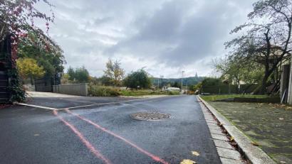 Bild: Petra Hartl
Zwei rote Striche quer über die Dostlerstraße zeigen, wo die „Mauer“ etwa entstehen müsste, damit sie sicherstellt, dass die Stadt die Kosten der Erschließung des Ostteils auf die Anwohner umlegen könnte. Im Hintergrund das noch unbebaute Grundstück, auf dem fünf Wohnhäuser gebaut werden können.