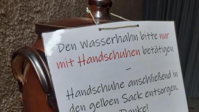 Bild: mng
Im Windfang zwischen Pfarrkirche und Altenheim wurde das Weihwassergefäß aufgestellt. Damit Weihwasser hygienisch entnommen werden kann, liegen zudem Einmalhandschuhe bereit.
