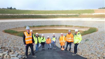 Bild: Kiver/exb
Vertreter von Uniper und der ausführenden Firma Kassecker stehen vor dem "Irlacher See". Hier ist der tiefste Punkt des rekultivierten Westfelds nahe des Steinberger Sees. Der Irlacher See dient als Sickerwassersammler.