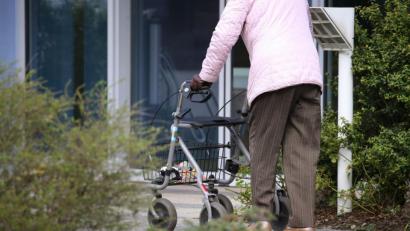 Symbolbild: Karl-Josef Hildenbrand/dpa
Ein ältere Frau mit Rollator geht vor dem Eingang eines Senioren-Wohnstiftes.