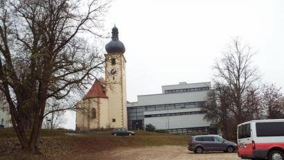 Bild: e
Der Blick vom Dorfplatz hinauf zur Kirche. Wo heute eine Parkpfläche zu sehen ist, soll einst eine Parkterrasse vom Dorfplatz zur Kirchen hinauf führen. Auf der linken Seite könnten sich die Planer bewachsene Gabionen vorstellen.