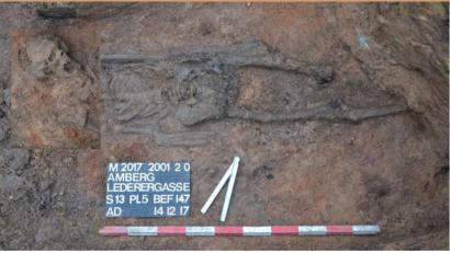 Bild: Scherbaum Bamberg
Das Skelett des Amberger Reiters lag seit dem achten Jahrhundert unter der Erde in der Lederergasse in der Altstadt von Amberg. Das Grab wurde 2017 von der Grabungsfirma Scherbaum in zwei Schritten ausgehoben, deshalb ist das Bild eine Fotomontage.