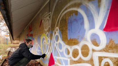 Bild: Wolfgang Steinbacher
Graffiti-Künstler „Aloha“ in seinem Element: Im Auftrag des TC Schanzl darf er sich an der Hallenaußenwand künstlerisch ausleben. In den vergangenen Jahren hatten Vandalen Schmierereien hinterlassen, die nun verschwinden.