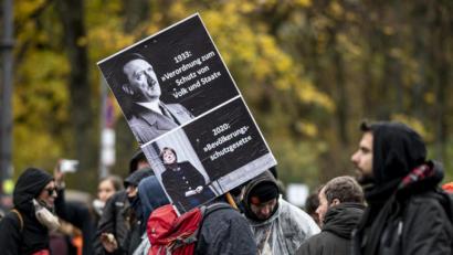 Bild: Fabian Sommer/dpa
Verqueres Demokratieverständnis: Ein Teilnehmer der Demonstration gegen die Corona-Einschränkungen hält ein Schild hoch auf dem Angela Merkel mit unter Adolf Hitler gleichgesetzt wird.