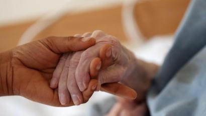 Bild: Oliver Berg/dpa
Eine Pflegerin hält im Altenheim die Hand einer Bewohnerin.