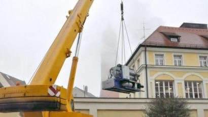 Bild: Karoline Gajeck-Scheuck/exb
Stadtwerke-Mitarbeiter und Lastenkran sorgen dafür, dass im Altstadtbereich der neue Gasmotor sicher schwebend im Blockheizkraftwerk Raseliushaus landet.