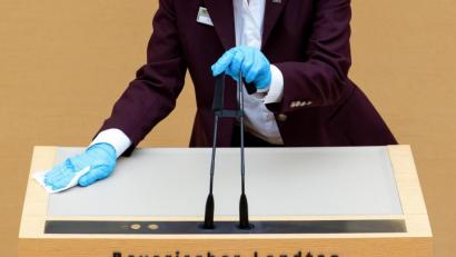 Bild: Sven Hoppe/dpa
: Eine Mitarbeiterin des Bayerischen Landtags desinfiziert das Rednerpult und die Mikrofone.