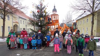 Bild: amö
Stolz präsentieren sich die Kindergartenkinder (links) und die Buben und Mädchen der Mittagsbetreuung (rechts) mit Walter Schauer (in der Mitte) vor dem Christbaum.