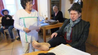 Archivbild: gm
Die Jubilarin Annemarie Neidl (rechts mit Hut) als Sketch-Laienspielerin und Patientin beim Arzt mit dem Fuß auf dem Tisch des Doktors. Die Lacher hat sie so natürlich stets auf ihrer Seite.