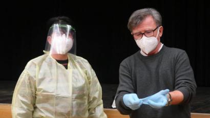 Bild: rhi
Zentrumsleiter Dr. Richard Wagner (rechts) händigte den Testern die Schutzkleidung aus und zeigte ihnen, wie sie sich ihrer nach dem Gebrauch wieder entledigen können, ohne sich selbst zu gefährden.