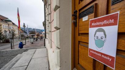 Bild: Armin Weigel
Ein Schild mit der Aufschrift "Maskenpflicht" in deutscher und tschechischer Sprache ist an einer Tür angebracht. Der Landkreis Regen ist weiterhin Corona-Hotspot.