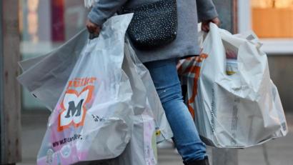 Bild: Martin Schutt/dpa
Eine Frau trägt Einkaufstüten durch das Stadtzentrum.