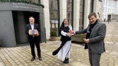 Bild: Sr. M. Sophia Schlembach/exb
Bei der Übergabe des Geschenkpackersl sowie des Glaskreuzes aus der Glashütte Lamberts auf dem Pfortenhof des Klosters, von links Armin Wolf, Äbtissin Laetitia Fech und KJF-Direktor Michael Eibl.