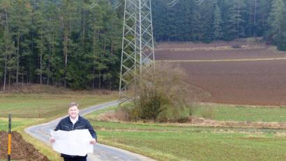 Bild: jp
Bürgermeister Stefan Braun erläutert bei einem Ortstermin an Hand eines Plans den geplanten Ausbau der Gemeindeverbindungsstraße zwischen Dettnach und Drahberg, der im kommenden Jahr über die Bühne gehen soll.