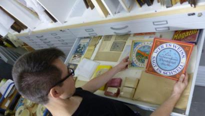 Bild: Simon Steiner/exb
Museumsmitarbeiter Simon Steiner bei der Arbeit im Außendepot im Keller des Verwaltungsgebäudes der Verbandskläranlage. Er sortiert Museumsobjekte in einen Grafikschrank ein.