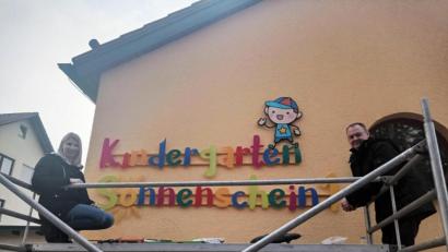 Bild: exb
Das neue Schild an der Fassade des Kindergarten Sonnenschein in Ebermannsdorf wird angebracht.