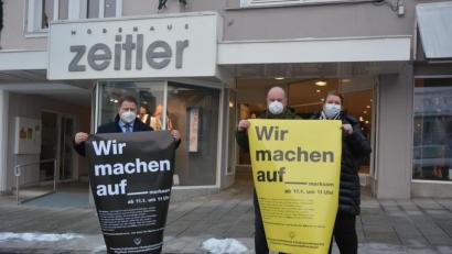 Bild: jr
Am Montag startete eine Plakataktion des bundesdeutschen Einzelhandels, mit dem Wunsch, dass sie ihre Geschäfte wieder öffnen dürfen, oder zumindest mit staatlicher Hilfe so entschädigt werden, wie die Gastronomie. Bei der Vorstellung in Mitterteich vor dem Modehaus Zeitler mit dabei waren, (von links), Bürgermeister und Gewerbefördervereinsvorsitzender Stefan Grillmeier, sowie Holger und Katrin Paschedag.