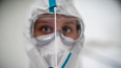 Symbolbild: Michael Kappeler
Eine Mitarbeiterin des medizinischen Personals betrachtet ein Wattestäbchen nach einem PCR-Abstrich zum Test auf Covid-19.