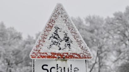 Bild: Peter Kneffel/dpa
Ein verschneites Verkehrsschild mit der Aufschrift „Schule“.