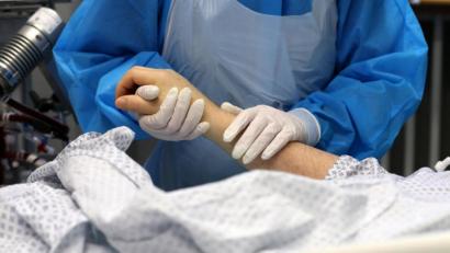 Bild: Bernd Wüstneck/dpa
Im Infektionszimmer für Covid-19-Patienten hält die Mitarbeiterin einer Intensivstation die Hand eines Patienten.