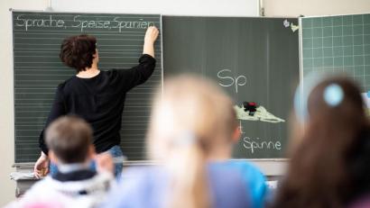 Symbolbild: Sebastian Gollnow/dpa
Eine Lehrerin schreibt in einer Schule an die Tafel.