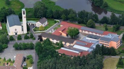 Archivbild: twi
Ein Teil des Wäldchens im Vordergrund wird der neuen Mehrzweckhalle weichen müssen. Die Digitalisierung in der Schule (rechts) schreitet voran.