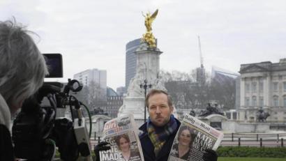 Bild: Kirsty Wigglesworth/dpa
Ein Fernsehjournalist hält zwei britische Zeitungen hoch, während er vor dem Buckingham Palace in die Kamera spricht. In ihrem mit Spannung erwarteten Interview hat Herzogin Meghan von Selbstmordgedanken sowie Rassismus innerhalb der königlichen Familie berichtet.