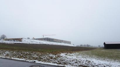 Bild: bey
Auf der landwirtschaftlich genutzten Fläche soll das neue Bauvorhaben der Firma Witron entstehen, das zum derzeit im Bau befindlichen Gebäue (oben, links) eine Verbindung haben soll. Die Gemeindestraße (im Vordergrund) muss laut Bürgermeister Reinhard Sollfrank ausgebaut werden.