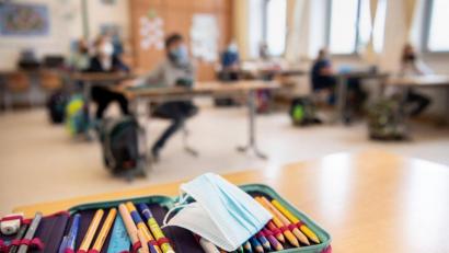 Bild: Matthias Balk/dpa
Der Ersatz-Mundschutz einer Schülerin liegt während des Unterrichts in einer vierten Klasse einer Grundschule in München auf dem Federmäppchen der Schülerin.