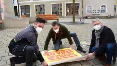 Bild: bey
Gemeinsam befestigen Bürgermeister Sebastian Dippold, Martin Neumann, Geschäftsführer des Kreisugendrings und Arno Speiser, Koordinierungs- und Fachstelle "Neustadt lebt Demokratie" einen Bodenaufkleber vor dem Neustädter Rathaus.