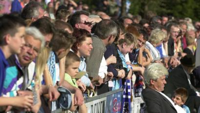 Archivbild: Ziegler
Werner Lorant (rechts, sitzend) mit den Fans im Nacken: Keine Scheu hatte der damalige Bundesligatrainer, sich direkt vor die Zuschauer auf einen Stuhl neben der Spielerbank zu setzen.