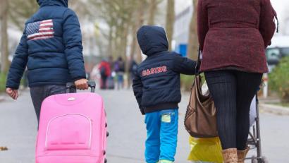 Symbolbild: Bernd Thissen/dpa
Eine Flüchtlingsfamilie mit Koffer und Kinderwagen.