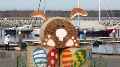 Symbolbild: Bernd Wüstneck/dpa
Eine Osterhasen-Skulptur aus Strohballen steht eingezäunt im Boddenhafen. Angesichts hoher Corona-Infektionszahlen wollen Bund und Länder das Reisen im Inland und ins Ausland möglichst stark bremsen.