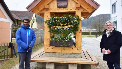 Bild: no
Der Vorsitzende des Gartenbauverein Illschwang, Lorenz Geitner (rechts), zeigt Pfarrvikar Thomas Sanikommula den geschmückten Dorfbrunnen in der Ortsmitte, gleich neben dem Rathaus.