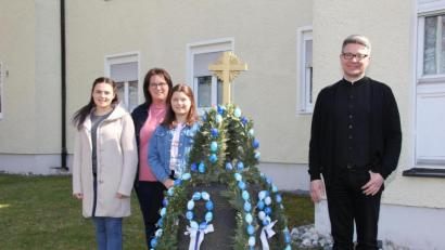 Bild: ads
Als Familienaktion gestaltet sich das Schmücken der alten Glocke im Pfarrgarten von St. Konrad für Manuela Weigl (hinten) und ihre beiden Töchter Leonie und Johanna (vorne, von links). Pfarrer Michael Jakob freut sich wie die Passanten an der geschmückten Osterglocke – heuer in den Bayernfarben.