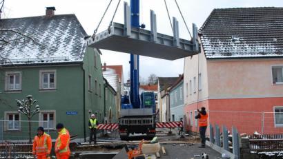 Bild: tss
Ein Autokran hievt das dritte Teil der neuen Brücke über den Floßbach auf das Widerlager.