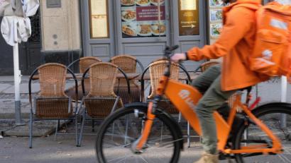 Bild: Sebastian Willnow/dpa
Der Fahrer eines Lieferdienstes fährt an dem Freisitz eines geschlossenen Restaurants vorbei.