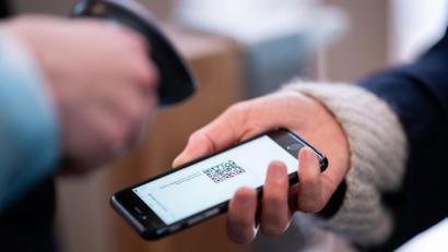 Bild: Daniel Reinhardt
Eine Frau lässt am Eingang eines Corona-Schnelltest-Zentrums einen QR-Code auf ihrem Smartphone abscannen.