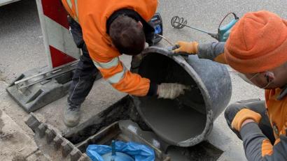 Bild: Stadt Neustadt/WN/exb
Martin Kißler (links) und Fabian Stich (rechts) beim Ausbetonieren des Sinkkastens im Gully mit dem Kinderhüpfball als Spezialkissen.