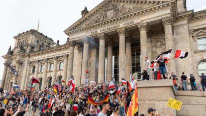 Archivbild: Achille Abboud, dpa
Teilnehmer einer Kundgebung gegen die Corona-Maßnahmen stehen Ende August 2020 auf den Stufen zum Reichstagsgebäude in Berlin, Reichsflaggen sind dabei zu sehen.